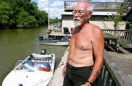 Dave Sutton, 74, with the 16-foot outboard boat which he used to rescue three young people whose canoe capsized off Cedar Island Monday.